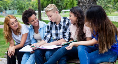 Four high school females and one male sitting outside studying English 